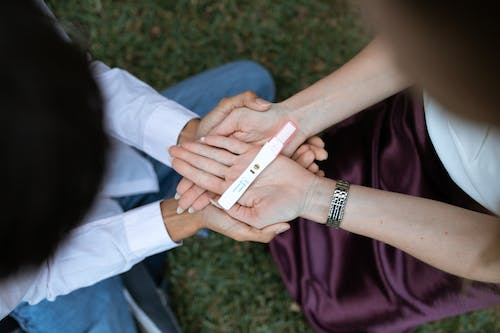 pregnancy test kit placed on a couple’s hand