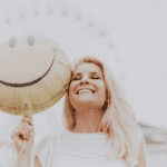 a woman smiling while holding a balloon