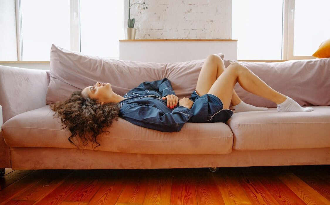 Woman holding her stomach while lying down on a couch