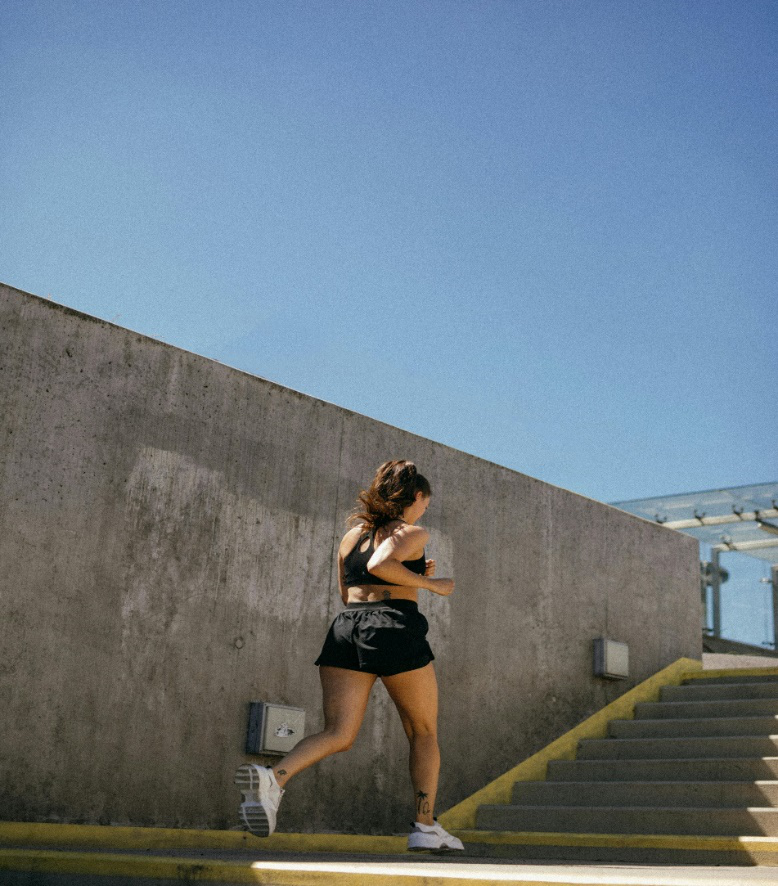Woman running in a black tank top and shorts.
