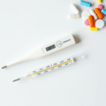 Thermometer and medicine on a white background